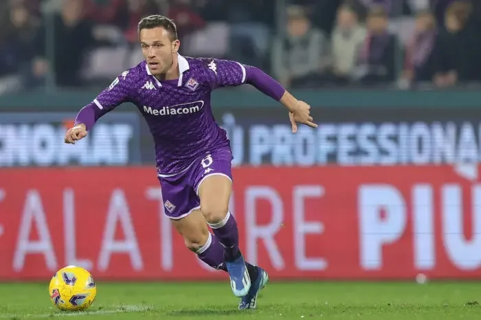 Arthur Melo in a purple Fiorentina kit dribbling a soccer ball during a Serie A match